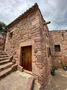 um edifício de tijolos com uma porta de madeira e escadas em Casa Castillo em Vilafamés