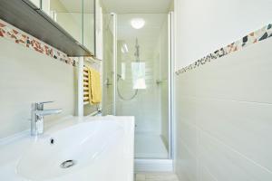 ein weißes Bad mit einem Waschbecken und einer Dusche in der Unterkunft Landhaus Lengg in Reit im Winkl