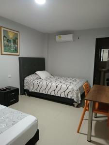 a bedroom with two beds and a table and a desk at Hotel Prado 53 in Barranquilla