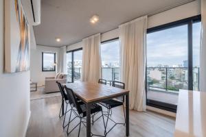 Un comedor con mesa y sillas y grandes ventanales. en La Vie Suite Palermo Hollywood, en Buenos Aires