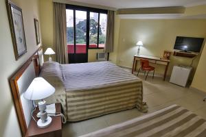 um quarto de hotel com uma cama grande e uma secretária em San Michel Hotel em São Paulo