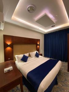 a bedroom with a large bed with blue sheets and a table at نزل المنتجع السياحية in Al Namas