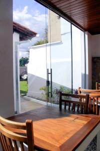 uma mesa de madeira e cadeiras num pátio com janelas de vidro em Pousada Villa Tiradentes em Tiradentes