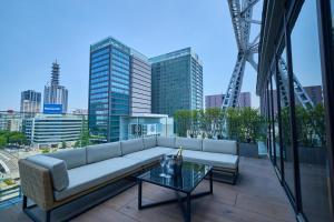 a couch on a balcony with a view of a city at The Tower Hotel Nagoya in Nagoya