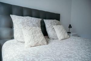 1 cama con almohadas blancas y cabecero negro en L'Alsace - tout confort, en Charleville-Mézières