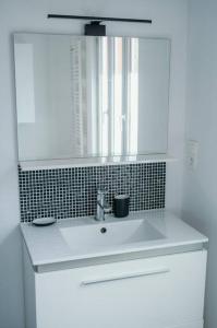 y baño con lavabo blanco y espejo. en L'Alsace - tout confort, en Charleville-Mézières