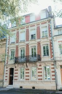 un gran edificio de ladrillo con ventanas y balcón en L'Alsace - tout confort, en Charleville-Mézières