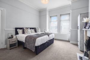 a white bedroom with a large bed and two windows at The Yorkshire Hosts - Central Castleford 4 Bed House - Free Parking in Castleford