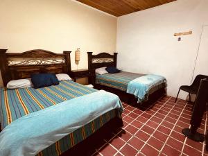 um quarto de hotel com duas camas e uma cadeira em El Extranjero Hostal em Antigua Guatemala