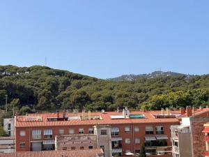 um grupo de edifícios com uma montanha ao fundo em Apartamento “La Caleta” em Calella