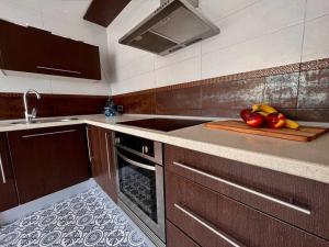 a kitchen with a sink and a cutting board with fruit at Apartamento “La Caleta” in Calella