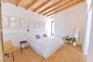 a white bedroom with a bed and a yellow chair at Casa Botijo - Natural Design in Linares de la Sierra