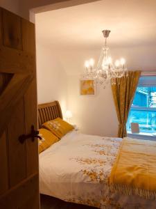 1 dormitorio con cama y lámpara de araña en Ty Cwtch en Dolgellau
