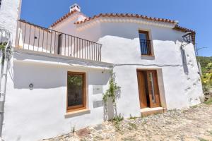 a white house with a balcony on a hill at Casa Botijo - Natural Design in Linares de la Sierra