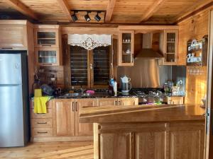 La cuisine est équipée d'armoires en bois et d'un réfrigérateur en acier inoxydable. dans l'établissement ORMAN AHŞAP EV, à Cayeli