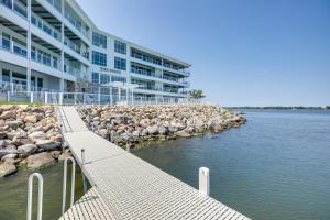 a dock in the water next to a building at Waterfront Watertown Condo with Patio and Pool Access! in Watertown