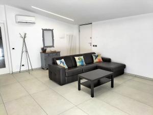 ein Wohnzimmer mit einem schwarzen Sofa und einem Tisch in der Unterkunft Le mimose in Alba Adriatica