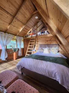 a bedroom with a large bed in a wooden house at Glamping El Muelle in Villa de Leyva