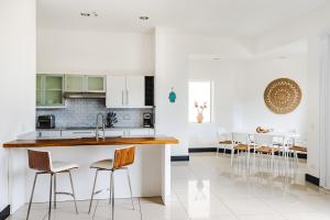 a kitchen with white cabinets and a counter with stools at Sea La Vie Suites - By The Beach in Tamarindo