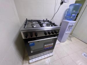 a stove in a kitchen with a bottle of water at Dinar apartments in Abu Dhabi