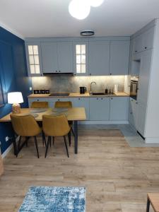a kitchen with white cabinets and a table and chairs at Miodowy Apartament in Złotów