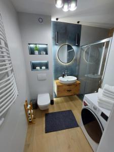a bathroom with a sink and a washing machine at Miodowy Apartament in Złotów