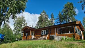 una casa di tronchi con un ampio portico e ampie finestre di Fin stuga nära sjö a Bollnäs