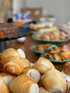 a bunch of bread on a table with plates of pastries at Pousada Villa Tiradentes in Tiradentes