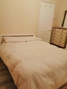 a bedroom with a white bed and a dresser at Angelica place in Portsmouth