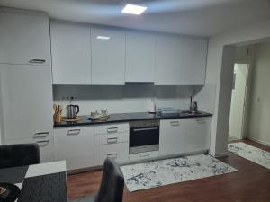 uma cozinha com armários brancos e um forno com placa de fogão em Apartments FOUR SEASONS em Sarajevo