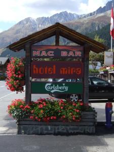 a sign for a hotel area with flowers in a parking lot at Hotel Mira in Sedrun
