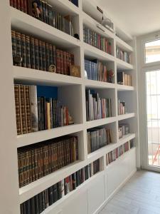uma biblioteca com prateleiras brancas cheias de livros em Appartamento Michelangelo em Novara