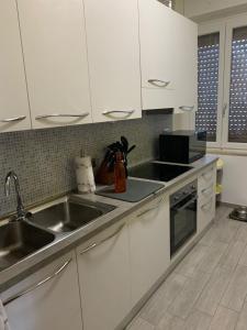 a kitchen with white cabinets and a sink at Appartamento Michelangelo in Novara