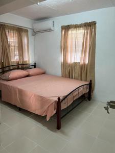 a bedroom with a bed with pink sheets and two windows at Chez Emmanuel in Gros Islet
