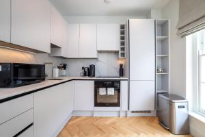 een witte keuken met witte kasten en een raam bij 3 Bedroom flat with Terrace in Central London in Londen