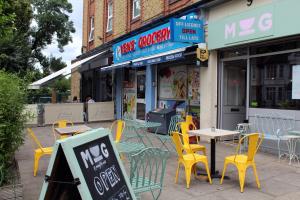 a cafe with yellow chairs and tables and a sign at Central London rooms in London