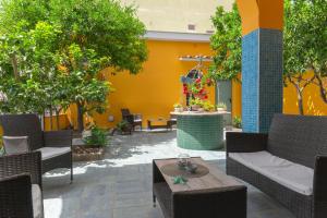 a patio with chairs and tables and a yellow wall at La Casa di Bianca in Follonica