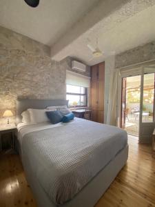- une chambre avec un lit et un mur en pierre dans l'établissement Πέτρινο σπίτι με κήπο και θέα στον ελαιώνα, Katouna Home II, à Katouna