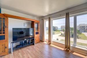 a living room with a flat screen tv and large windows at West of the Moon Ocean Apt with Beach Access! in Emerald Isle