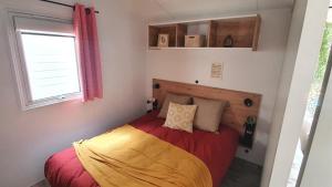 1 dormitorio con 1 cama con manta roja y amarilla en Camping Ty Nénez, en Pont-Scorff