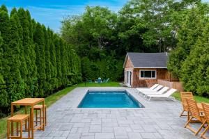 un patio trasero con piscina y sillas y una casa en Cozy Greenport Cottage, en Greenport