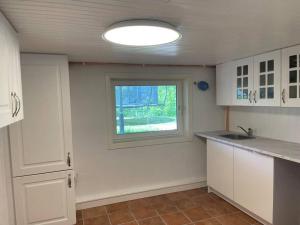 una cocina con armarios blancos y una ventana en Fin Sentralt Hybel i Drammen en Drammen