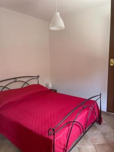 uma cama vermelha num quarto branco com um cobertor vermelho em The Garden House Relax em Rocca di Papa