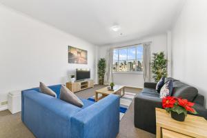 a living room with two blue couches and a tv at Goldsbrough 2 bedrooms split apartment in Sydney