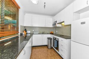 a kitchen with white cabinets and black counter tops at Goldsbrough 2 bedrooms split apartment in Sydney