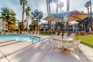 a table and chairs with an umbrella next to a pool at Canyon Shores Desert Escape in Cathedral City