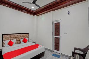um quarto com uma cama com almofadas vermelhas e uma cadeira em Flagship Shree Shyam Residency em Nova Deli