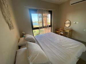 a bedroom with a white bed and a window at Lily's Place - Scenic Lagoon View at Tawila, Gouna in Hurghada