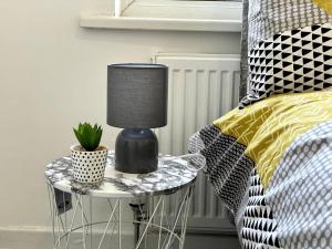 a table with a lamp on it next to a bed at Modern House Liverpool in Liverpool