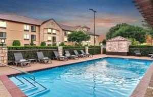 a swimming pool with chairs and a building at Best Western Plus Lewisville Flower Mound in Lewisville